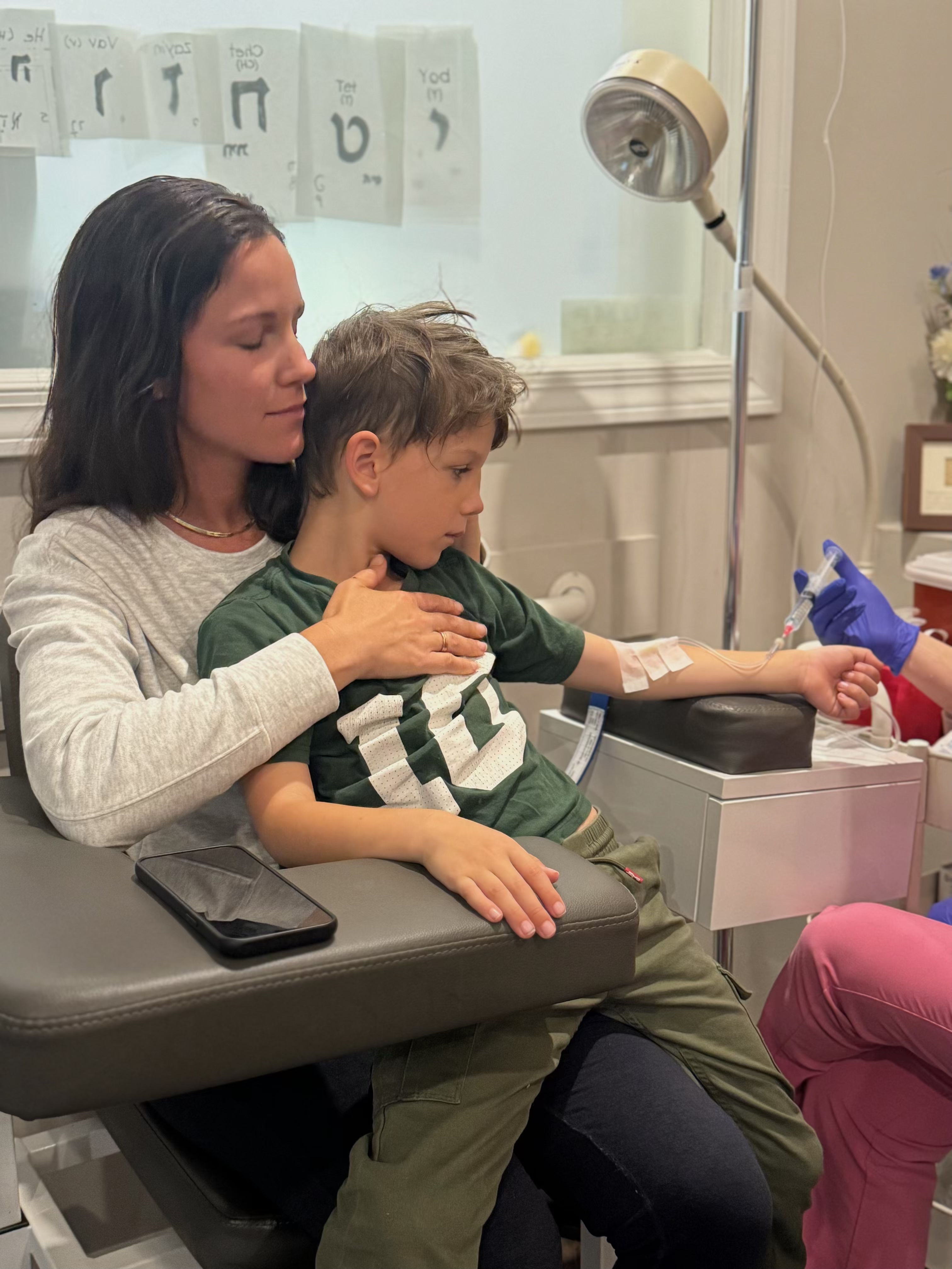 Tara holding her son during a hospital treatment, eyes closed